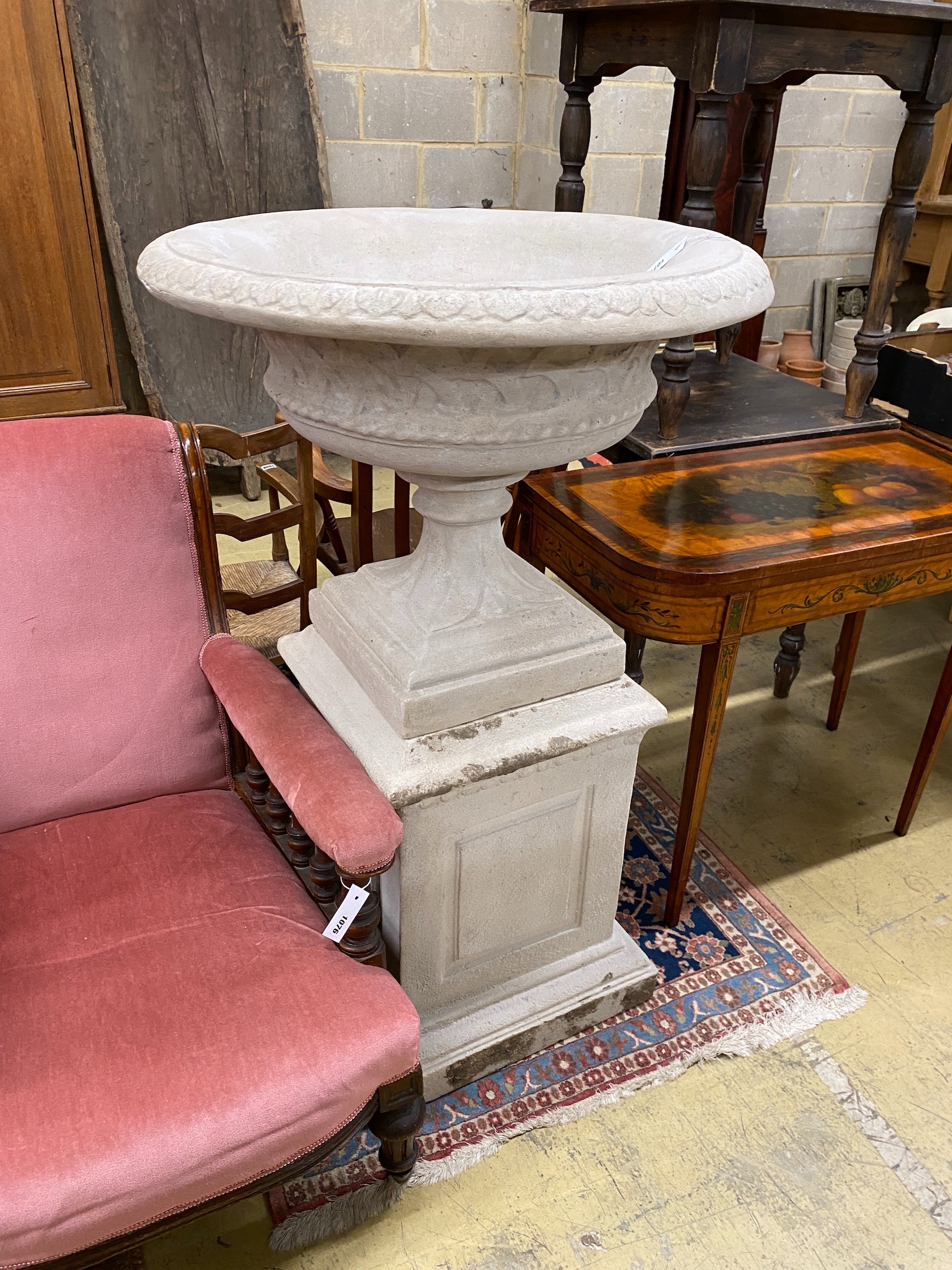 A faux stone circular garden urn on a square plinth, diameter 75cm, height 120cm